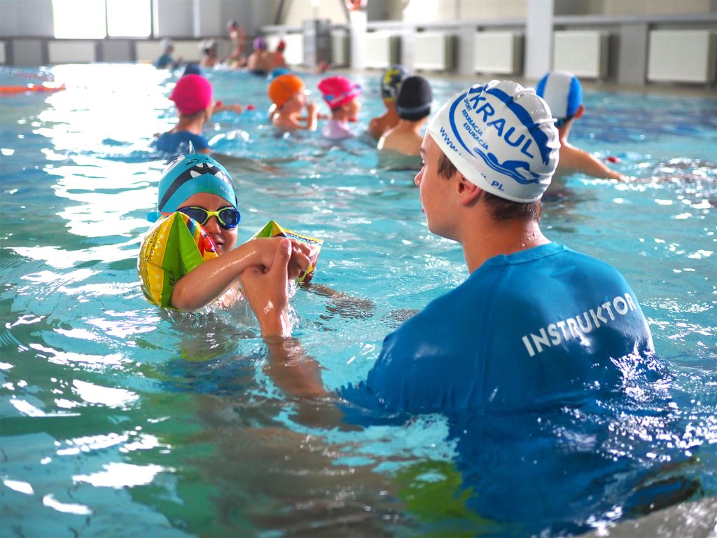 instruktor uczy małe dziecko pływać